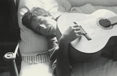 a man sleeping with his head on a guitar