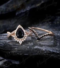 two different types of rings on top of a rock, one with black and white stones