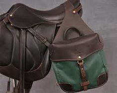 two brown and green saddles sitting on top of each other in front of a gray wall