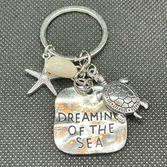 a keychain with a turtle and starfish on it that says dreaming of the sea