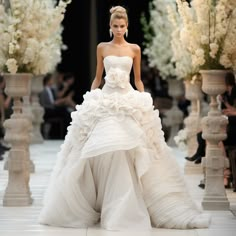 a model walks down the runway in a white wedding dress with large flowers on it