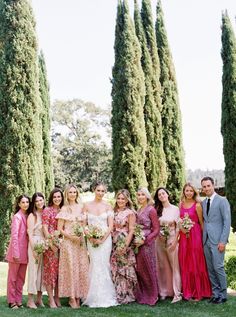 a group of people standing next to each other in front of some tall trees and bushes