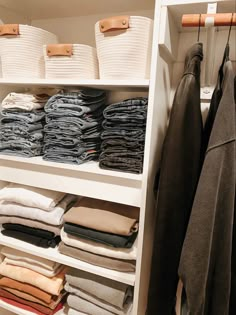 an organized closet with folded clothes and baskets