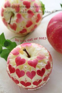 two apples with hearts painted on them sitting next to leaves and one apple has a bite taken out of it