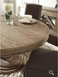 a wooden table with two chairs and a plate on it in front of a window