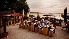 people are sitting at tables near the water