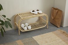 two pairs of shoes are sitting on a bamboo shelf next to a rug and bag