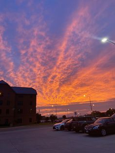 a parking lot filled with lots of parked cars under a colorful sky at sunset or dawn