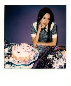 a woman sitting at a table with a cake in front of her