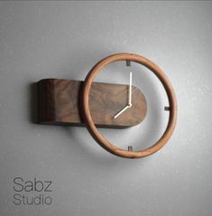 a wooden clock mounted to the side of a wall with a metal ring around it