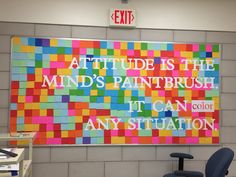 an office cubicle with a colorful sign on the wall above it that reads, attitude is the mind's paintbrush it can color any situation