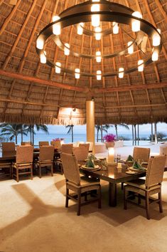 the inside of a restaurant with tables, chairs and umbrellas over looking the ocean