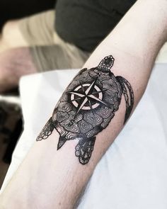 a turtle with a compass tattoo on its arm