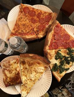 four slices of pizza on paper plates with water bottles