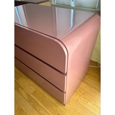 a shiny pink bed frame with drawers on the bottom and sides, in front of a window