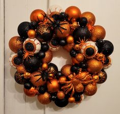 an orange and black wreath with spider decorations