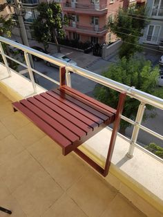 a wooden chair sitting on top of a balcony next to a building with cars parked in front of it