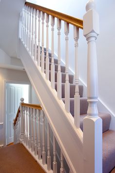 a staircase with white railing and brown carpet