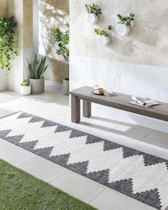 a bench sitting in the middle of a room with potted plants on either side