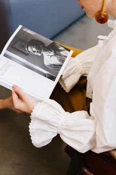 a woman sitting down reading a magazine