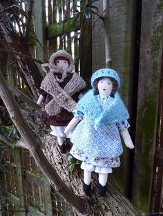 two dolls are sitting on a tree branch