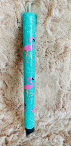 a pink flamingo on turquoise glittered paper next to a blue lighter