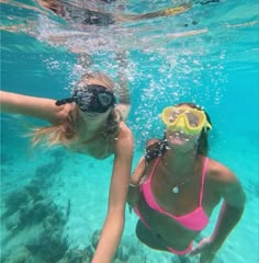 two young women swimming in the ocean with goggles on