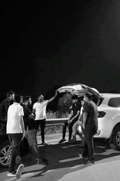 a group of people standing around a white car