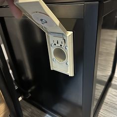 a person is opening the door to a black cabinet with an electrical outlet on it