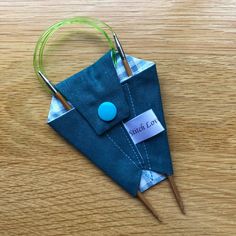 an origami pin cushion with needles in it on a wooden table next to some thread