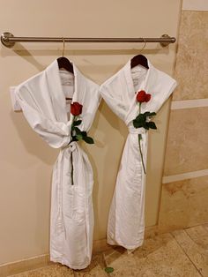 two robes with roses tied to them hanging on a wall