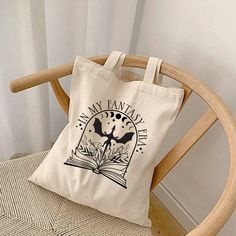 Embark on a literary journey with My Chapters & Charms Co. canvas tote! Crafted to hold your favorite books snugly, it's the perfect companion for any adventure. Whether you're exploring the streets of a new city or simply curling up at your favorite cafe, let this tote be your faithful sidekick. With its sturdy construction and whimsical design, it's a must-have for book lovers everywhere. TOTE DETAILS: This 100% cotton bag comes in one size - 15" x 16"- perfect for everyday wear. The bag features 20" handles (made from the same canvas), making it easy to carry even with a week's worth of shopping. .: 100% cotton canvas .: Available in natural .: Heavy fabric  .: Sewn-in label *RETURNS AND EXCHANGES NOT ACCEPTED* *PLEASE REVIEW PROCESSING TIME AND ESTIMATED SHIPPING DATES* Dragon Book, Bookstore Cafe, Gift For Book Lover, Whimsical Design, Book Dragon, Fantasy Dragon, Book Lovers Gifts, Tote Bag Design, Cotton Totes