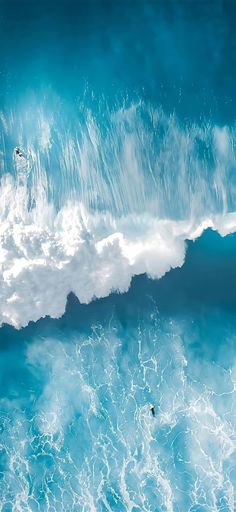 an aerial view of the ocean waves and surfers