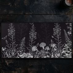 a black and white photo of flowers on a wooden table next to a teapot