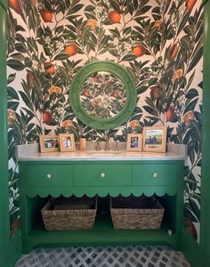 a green cabinet with two baskets under it in front of a wallpapered bathroom