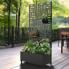 an outdoor planter with potted plants in it on a deck next to a table and chairs