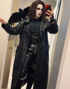 a man dressed in black is taking a selfie with his cell phone while wearing a costume