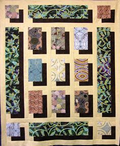 a quilted wall hanging on the side of a black wall with green and brown squares