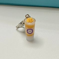 a small glass filled with liquid sitting on top of a white table next to a keychain