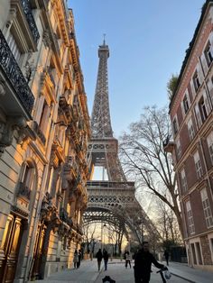 the eiffel tower is lit up at night with people walking by in the foreground