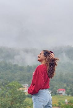 a woman with her hair blowing in the wind looking up into the sky and mountains