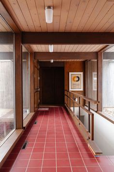 a long hallway with red tile floors and wood paneling