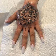 a woman's hand with an intricate tattoo on it