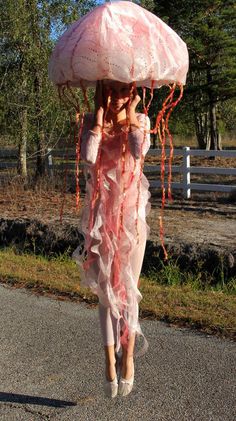 a woman walking down the street in a pink dress with an umbrella over her head