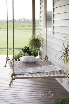 a porch swing with pillows and plants on it