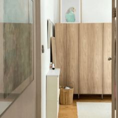 an open door leading to a bathroom with wooden cabinets and white rugs on the floor