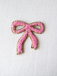 a pink bow brooch sitting on top of a white cloth