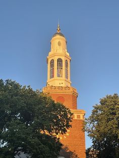 a tall tower with a clock on it's side next to trees and buildings