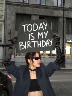 a woman holding up a sign that says today is my birthday