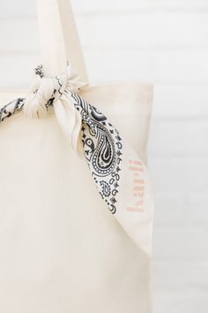 a white tote bag with a black and white paisley print on the front pocket